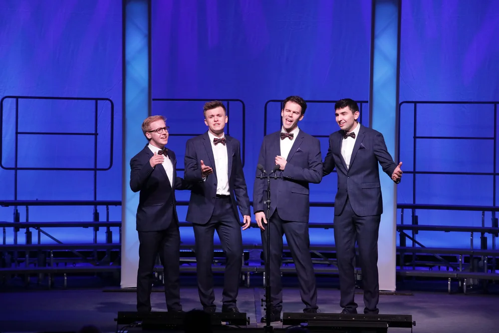 Sound Hypothesis singing on stage in blue suits